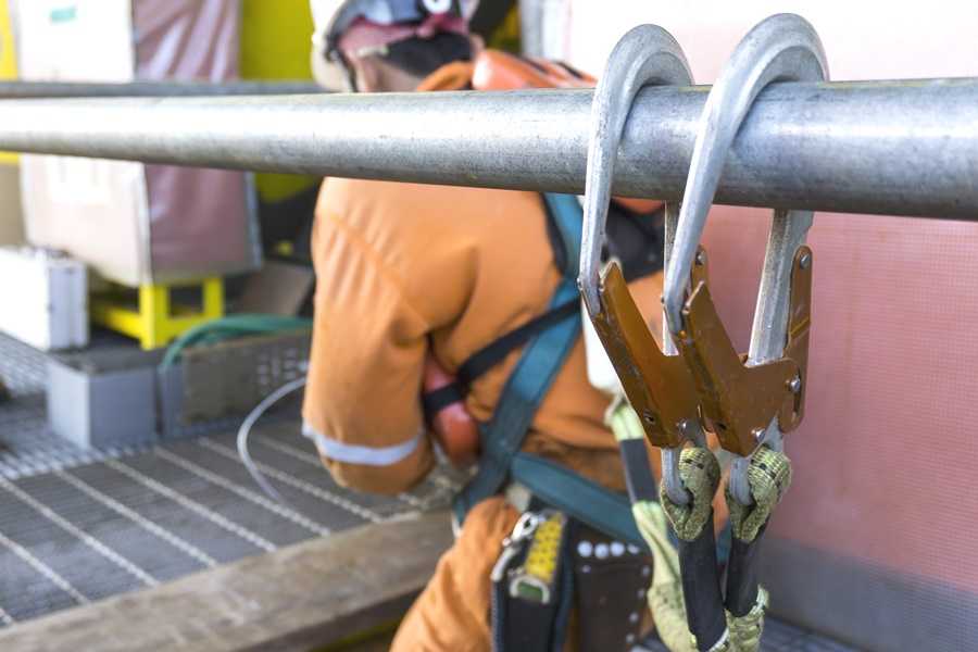 employee secured to railing using appropriate fall arrest gear