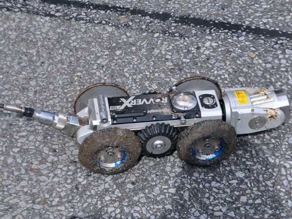 a small metal robot with a camera on the front and mud on its tires
