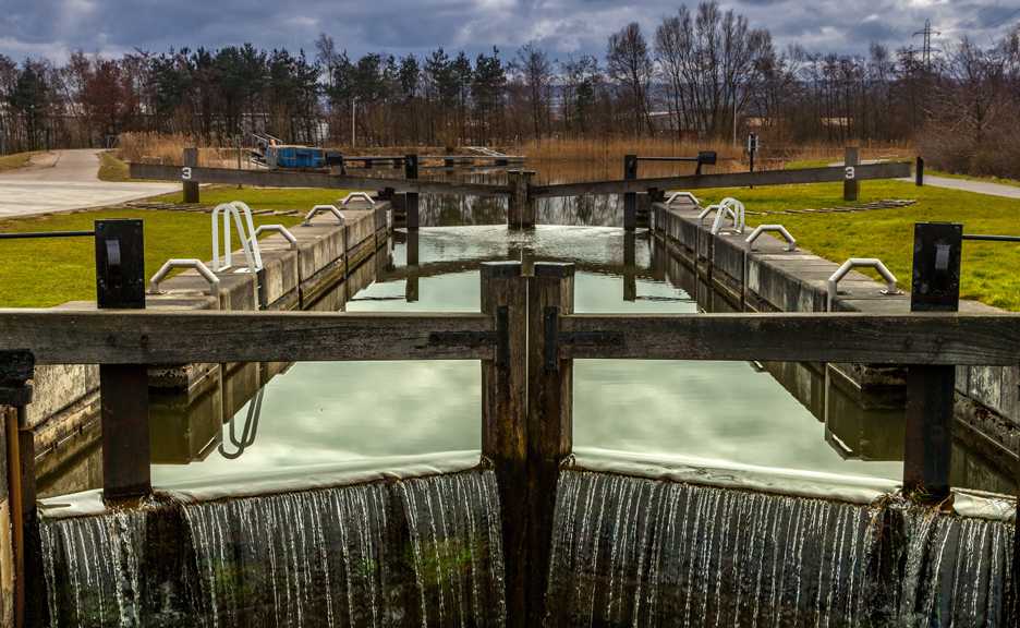 water from a pond flows out of two sluices forming a waterfall