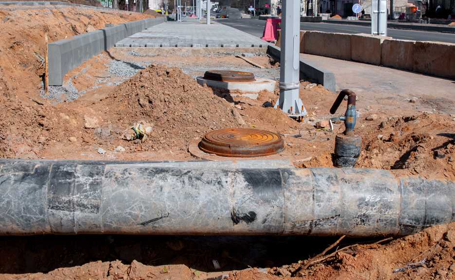 an unearthed metallic pipe lays in redish dirt